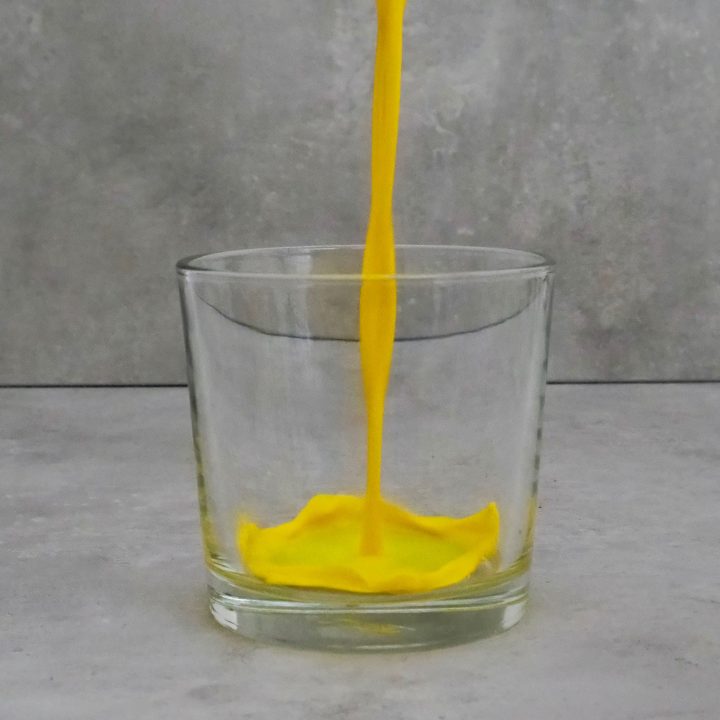 Goldene Milch fließt zentral in ein kleines Glas