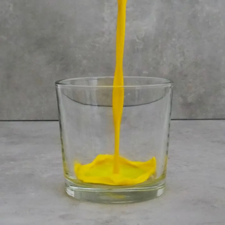 Goldene Milch fließt zentral in ein kleines Glas