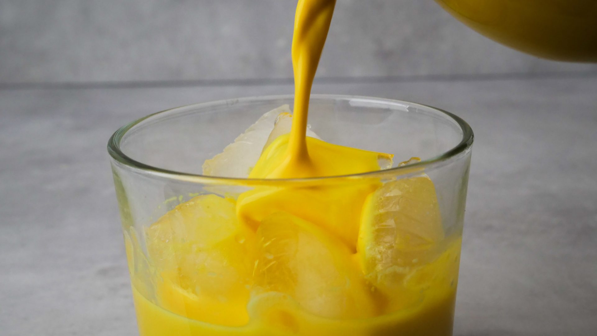 Golden Milk - Die gelbgoldene Milch wird über Eis ins Glas geschüttet