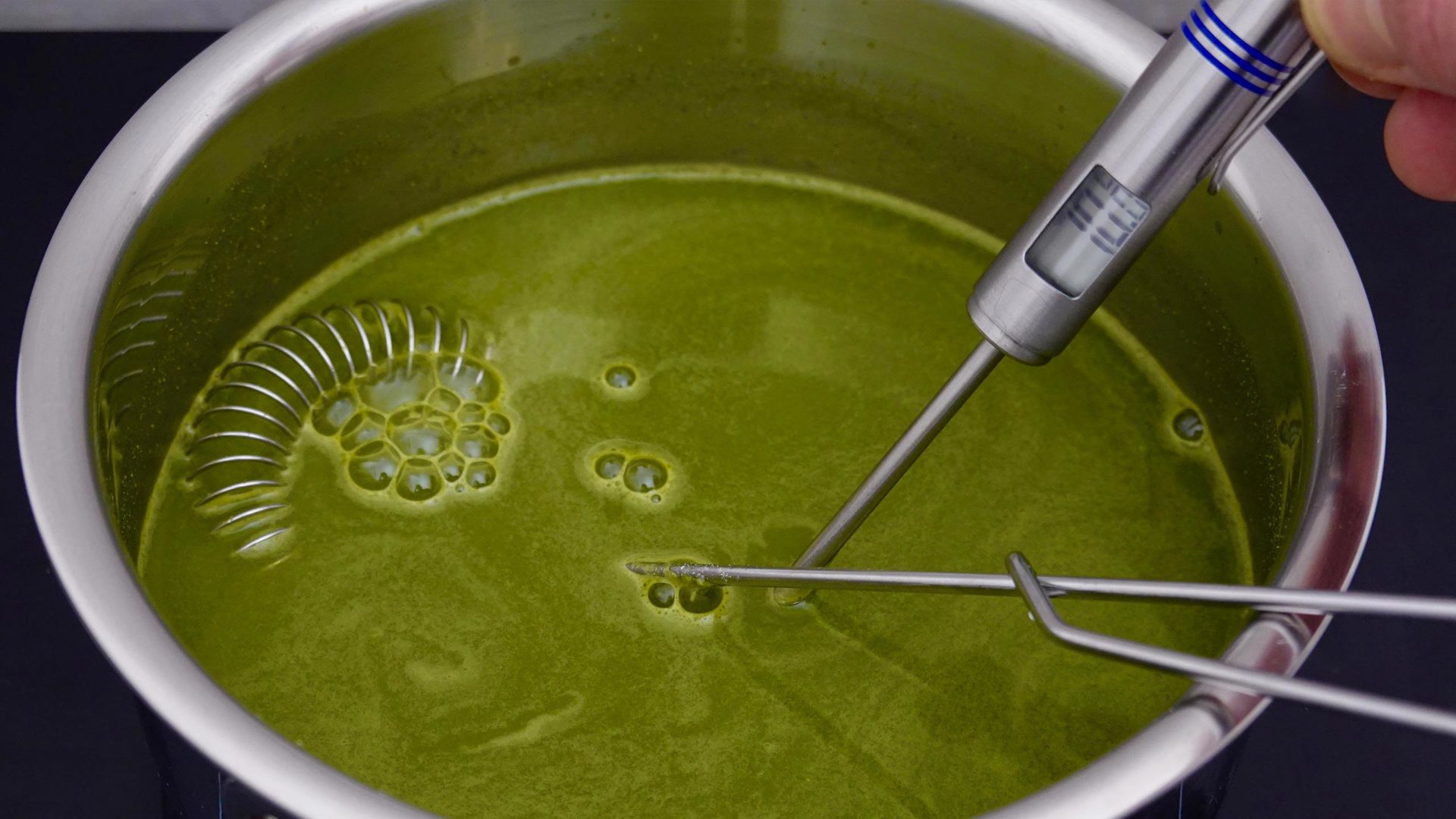 Cabbage drink - kale juice in pot with thermometer and spiral whisk