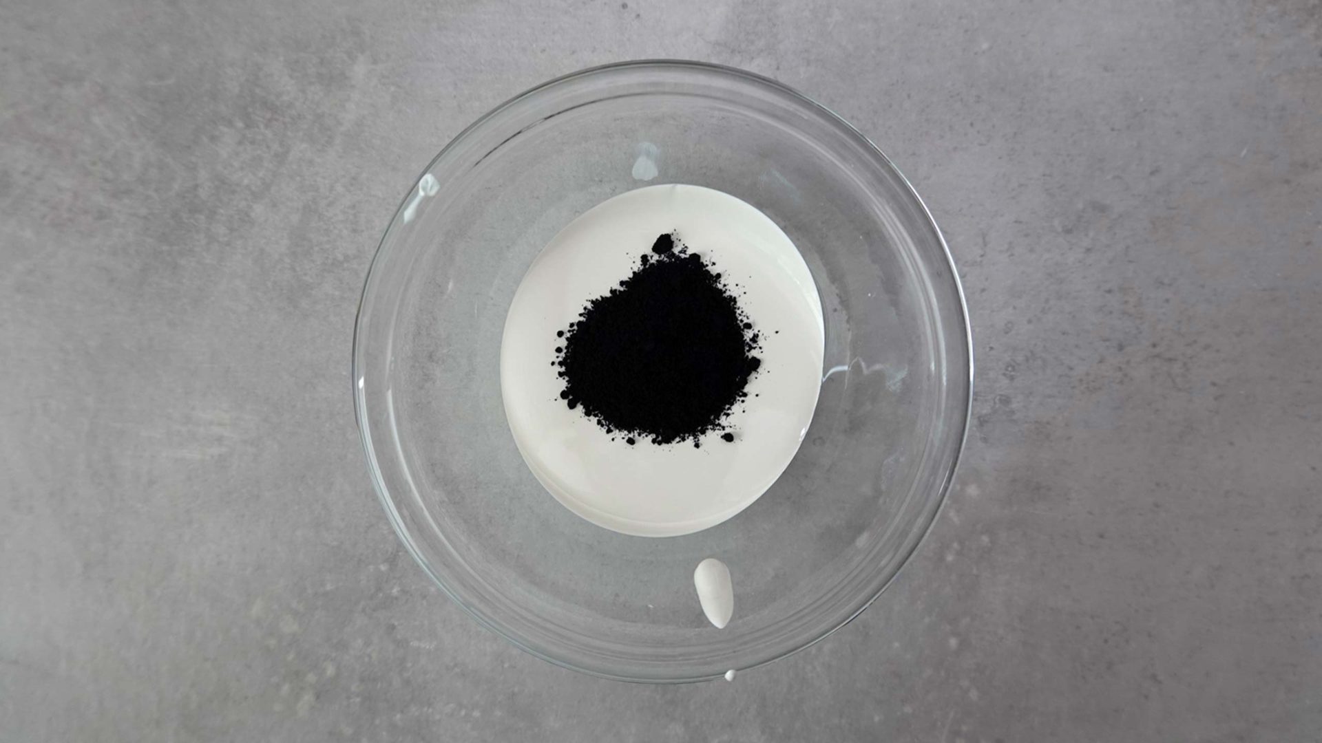 Weiße Schokoladenmasse mit schwarzem Farbpulver in Glasschüssel