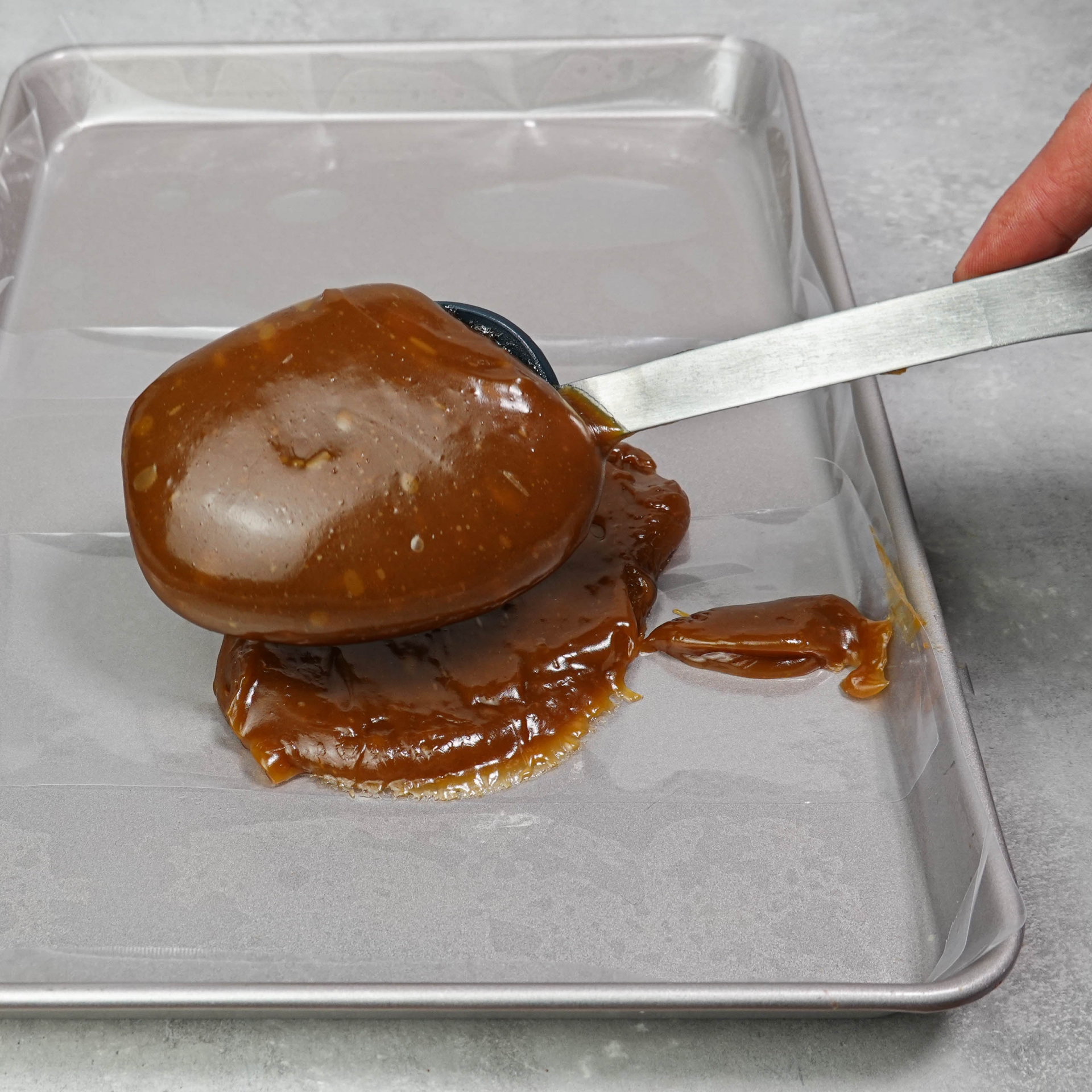 The deep brown caramel is spread on a small baking tray