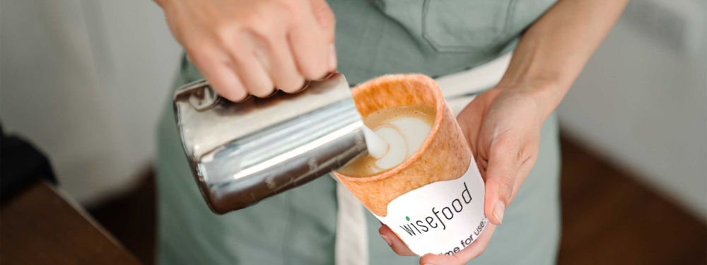 Aufgeschäumte Milch fließt in einen ganz besonderen Kaffeebecher: Den essbaren von Wisefood.