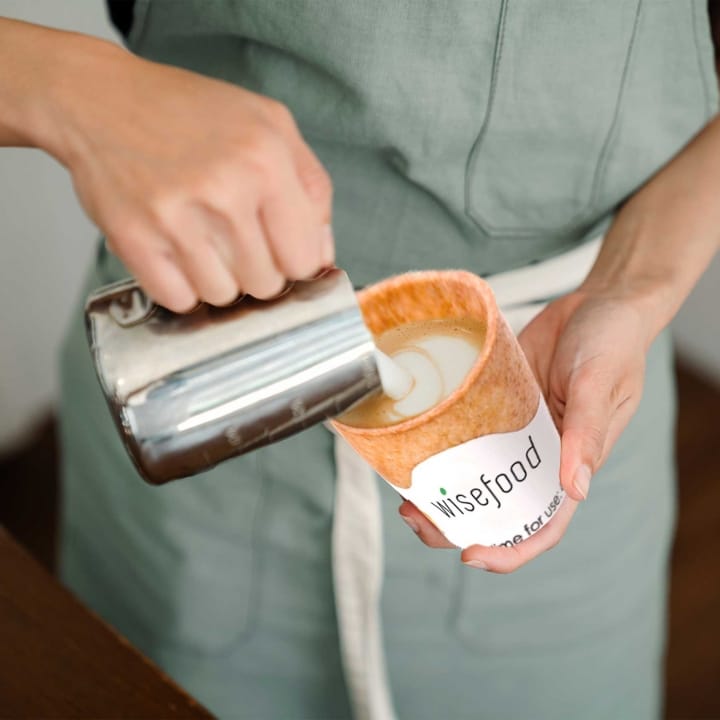 Aufgeschäumte Milch fließt in einen ganz besonderen Kaffeebecher: Den essbaren von Wisefood.